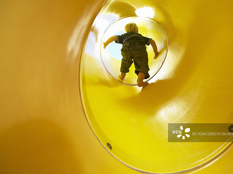 男孩(2-4)爬出黄色的游戏隧道，后视图图片素材