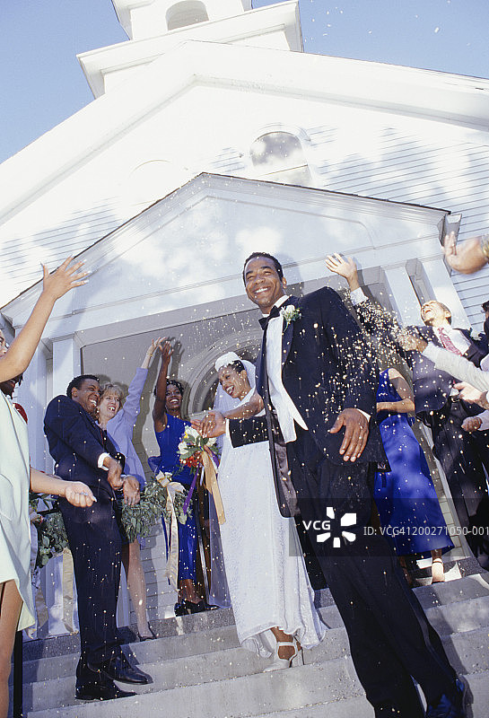 宾客在教堂前向新郎新娘扔大米，低角度观看图片素材