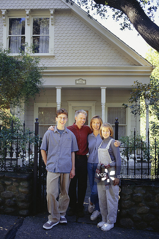 家庭与十几岁的儿子(16-17)和女儿(14-15)站在房前，肖像图片素材