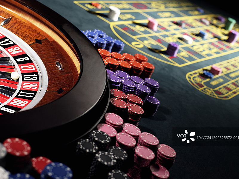 在赌桌上，筹码堆在轮盘赌轮周围图片素材