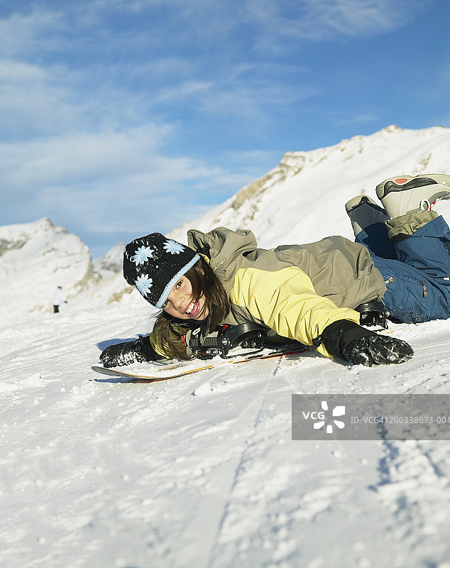 女孩(9-11)躺在滑雪板上，微笑着，肖像图片素材