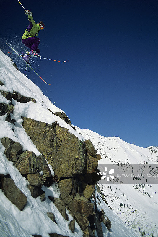 滑雪者跳过岩石，雪鸟，美国犹他州，低角度的观点图片素材