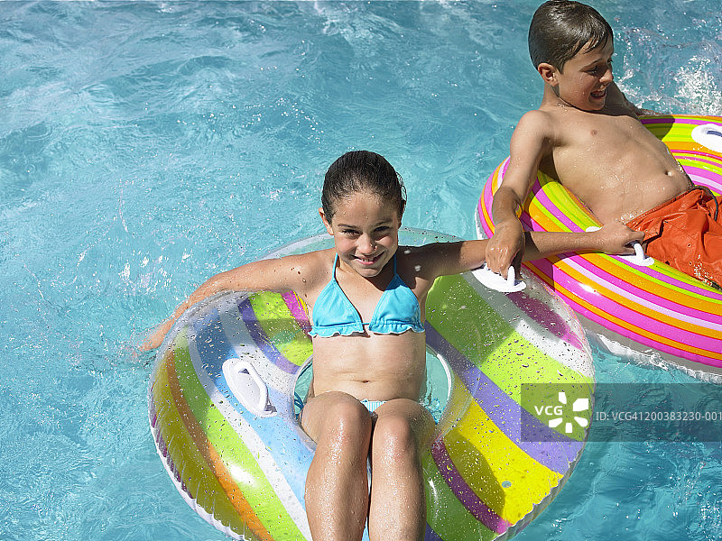 弟弟和妹妹(9-12)坐在游泳池的充气上图片素材