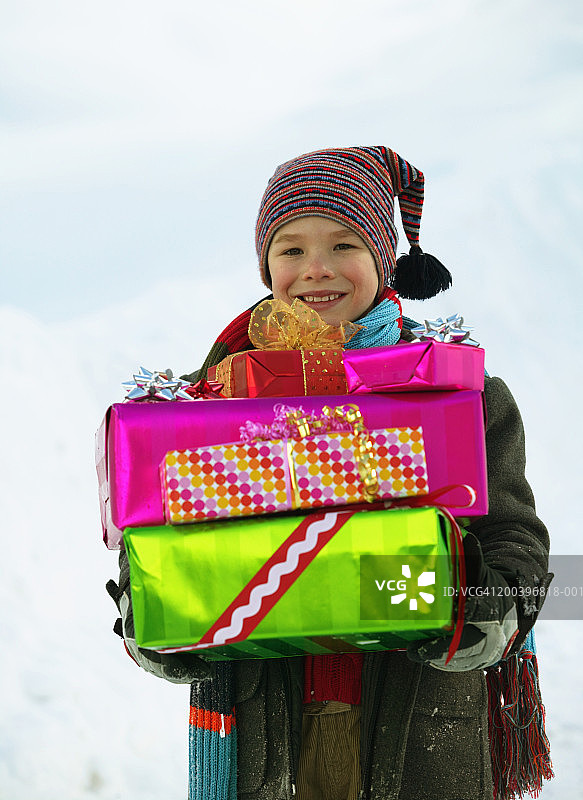男孩(8-10)在雪中拿着礼物，微笑着，肖像，特写图片素材