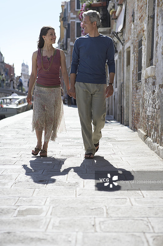 意大利，威尼斯，一对夫妇走在运河边的街道上图片素材