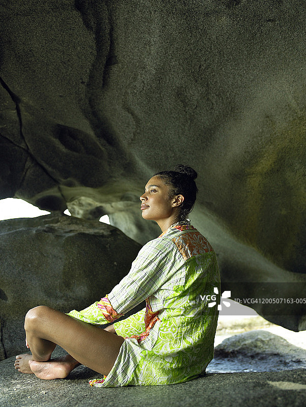 年轻女子坐在海边的岩石上图片素材