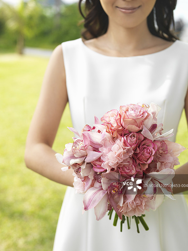 新娘手捧花束，面带微笑，在户外，中段图片素材