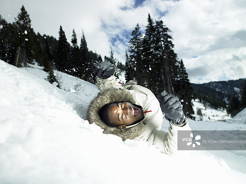 一个男人在雪地里从山上滚下来，叫喊着图片素材