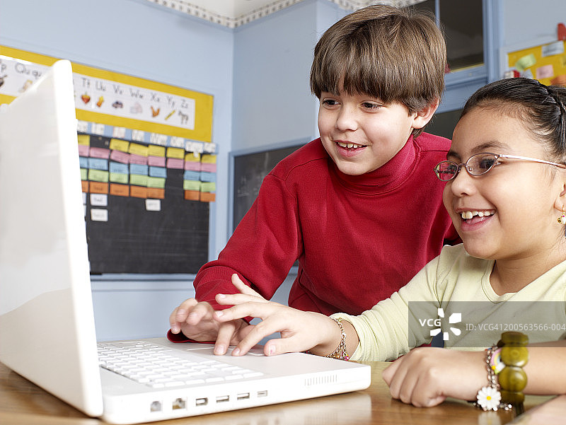男孩和女孩(6-7)在教室使用笔记本电脑图片素材