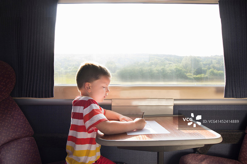 小男孩拿着铅笔和纸在火车上图片素材