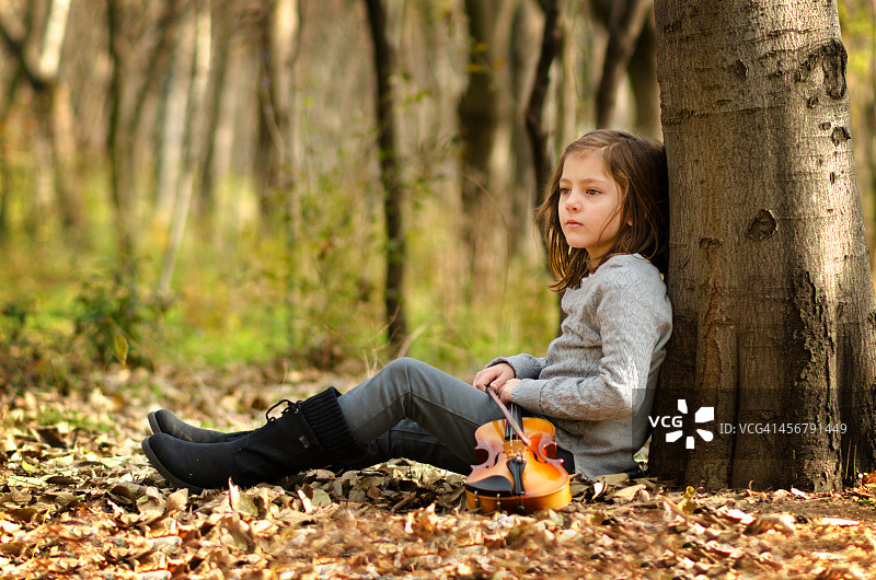 女孩在树林里练完小提琴后休息图片素材