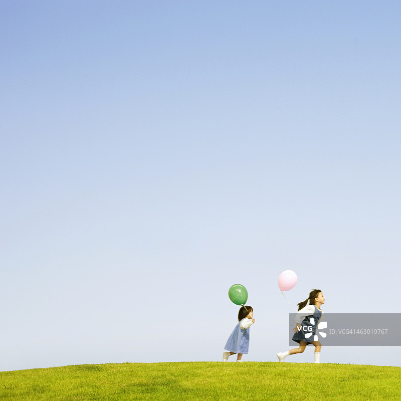 两个女孩拿着气球跑图片素材