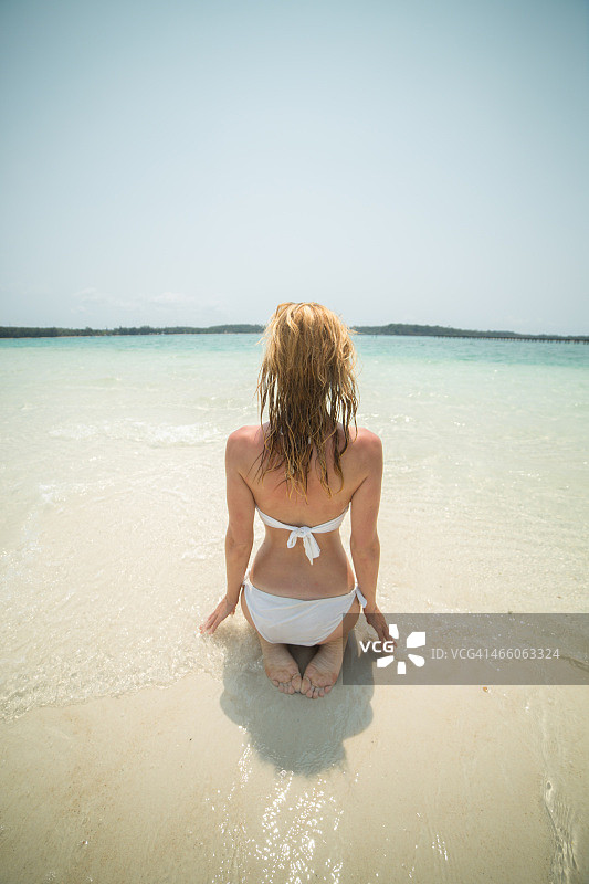 一个女人跪在热带海滩上图片素材