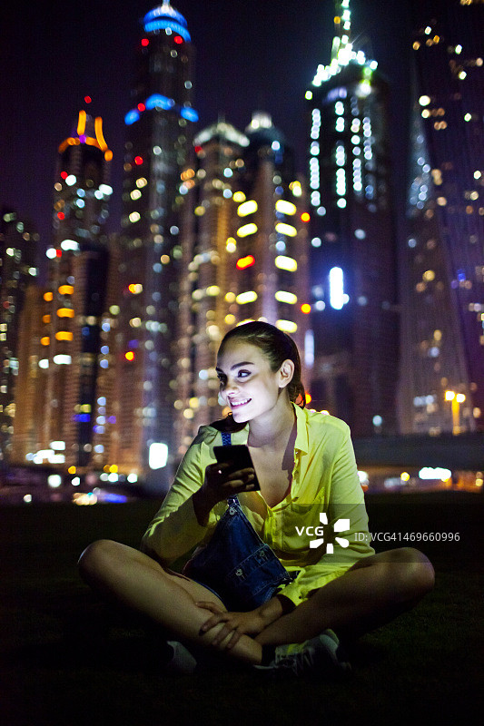 一个女人在迪拜码头用智能手机发短信图片素材