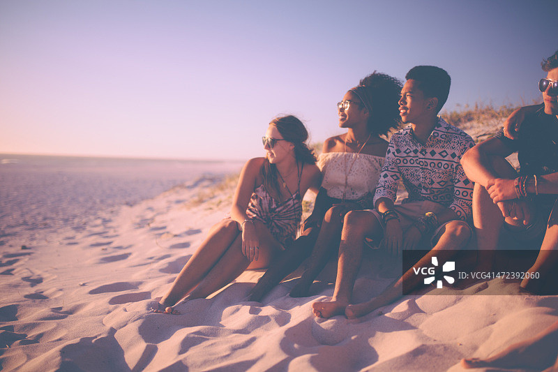 一群混合种族的朋友在海滩上看日落图片素材