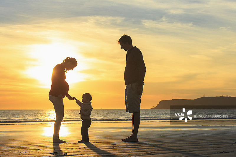 家庭和蹒跚学步的儿子在海滩上玩日落，圣地亚哥，加利福尼亚，美国图片素材