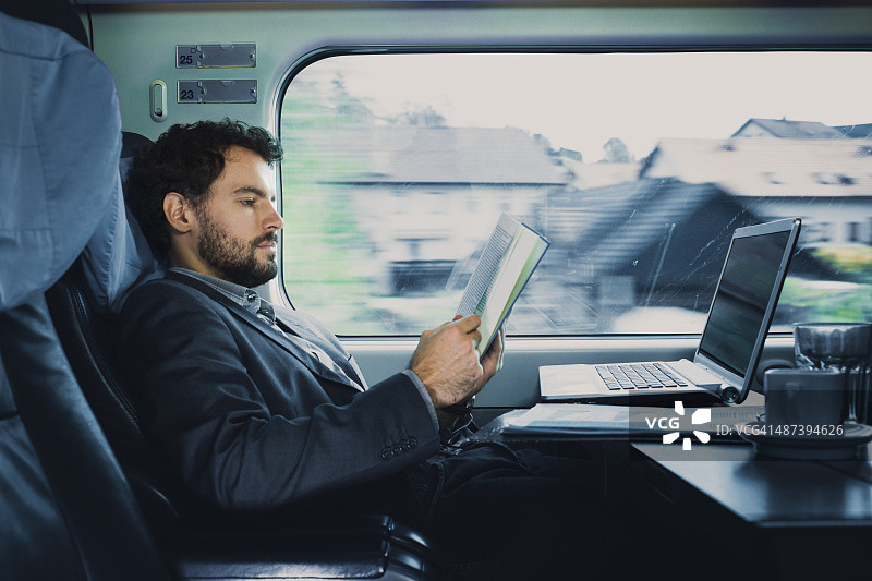 ． 坐在火车窗户旁边看书的商人图片素材