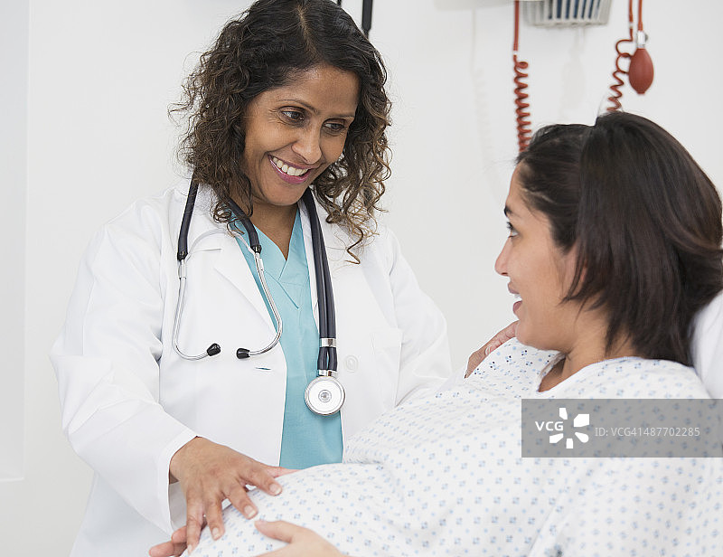混血医生检查孕妇的腹部图片素材