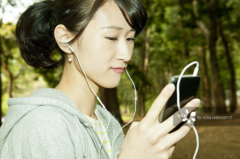 女人在公园里用智能手机听音乐图片素材