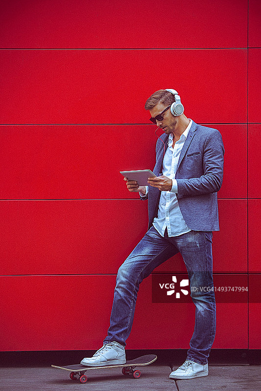 红墙旁的年轻帅哥在用平板电脑图片素材
