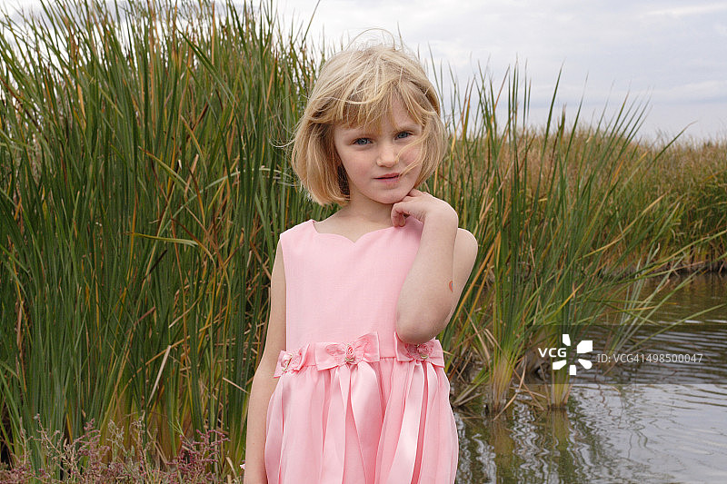 穿着粉红色裙子的女孩在湿地草地上图片素材