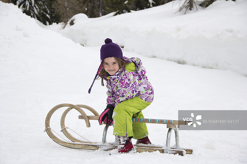 奥地利，卡林西亚，格蒙德，带着雪橇微笑的小女孩图片素材