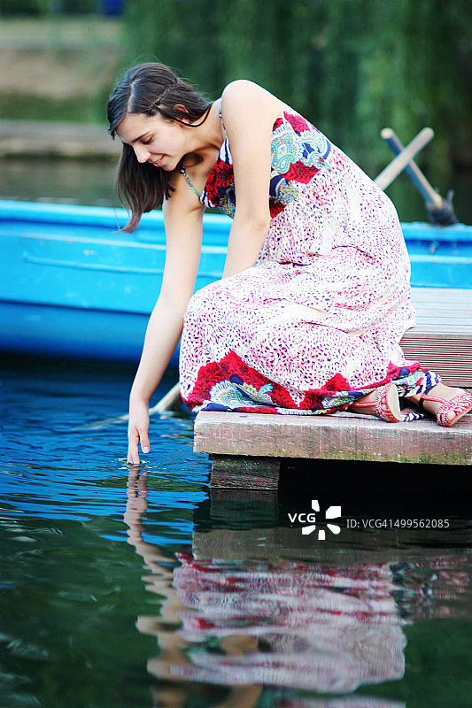 浮舟上的女孩俯身，手伸进水里图片素材