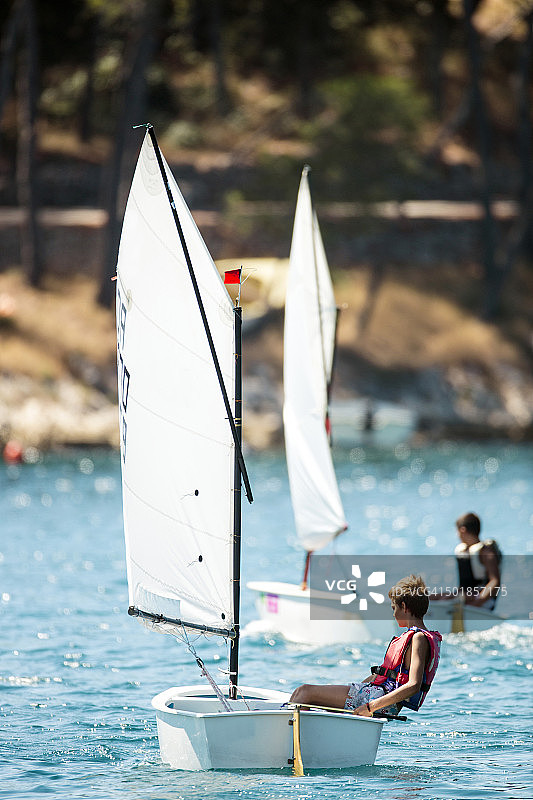克罗地亚赫瓦尔岛，两个男孩在帆船上比赛图片素材