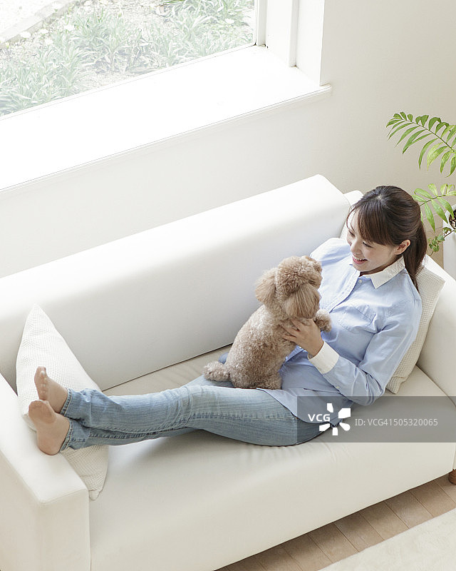 和宠物狗坐在沙发上的女人图片素材