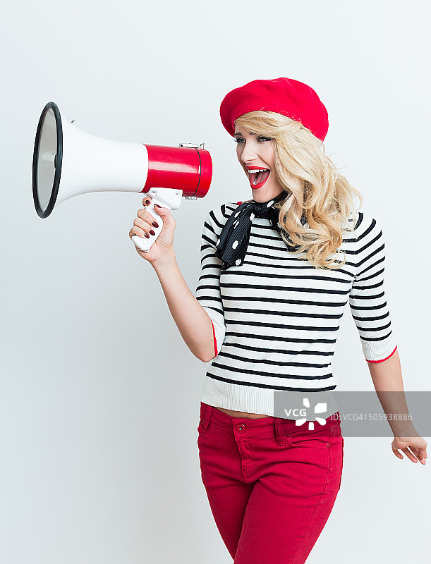 戴着红色贝雷帽的金发法国女人对着扩音器大喊图片素材