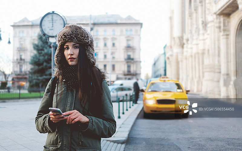 一个女人在城市里叫出租车的冬季肖像图片素材
