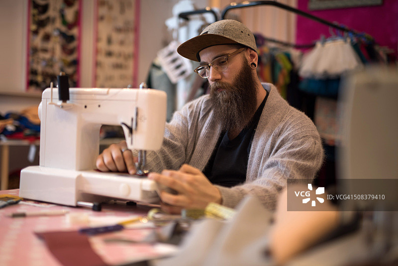 男潮人裁缝在缝纫机上工作。图片素材