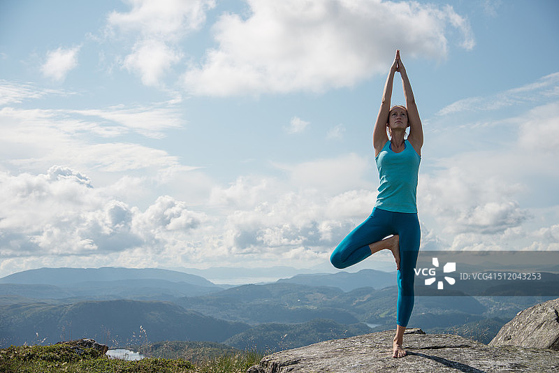 一个在山顶上练习瑜伽的女人图片素材