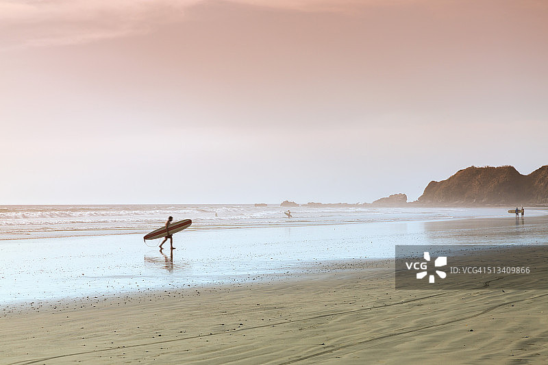 哥斯达黎加，日落时分，冲浪者在海滩上散步图片素材