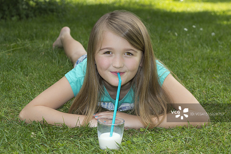 女孩躺在草地上用吸管喝牛奶图片素材