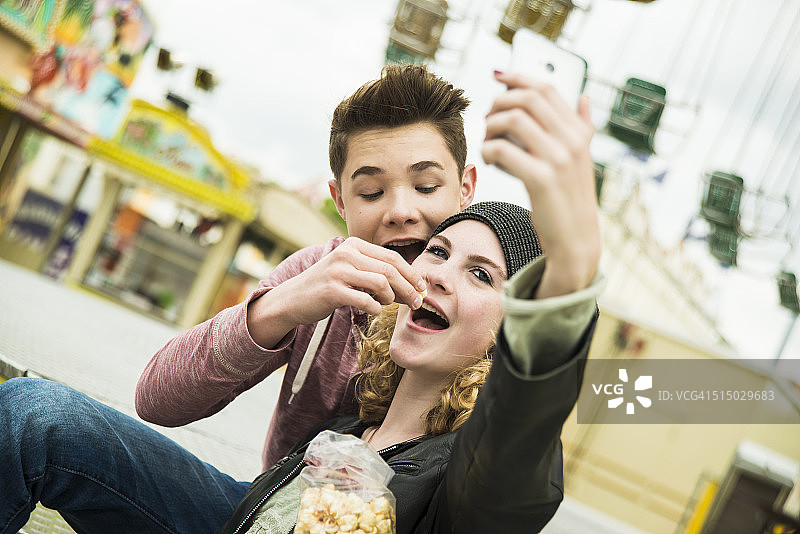 青少年夫妇的肖像与爆米花拍摄自己在游乐场图片素材