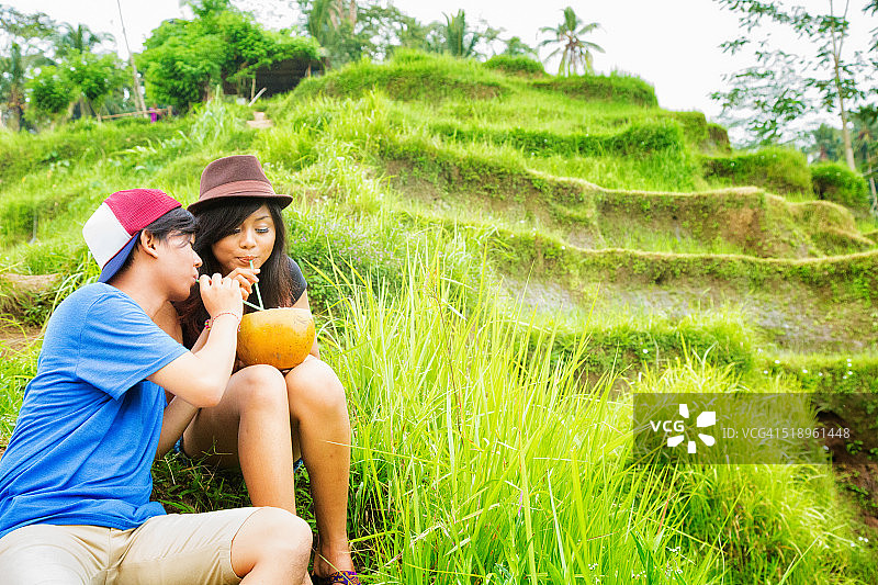 年轻的印尼朋友们在稻田里享受新鲜的椰子图片素材