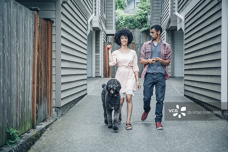 混血母亲和儿子在郊区公寓小区遛狗图片素材