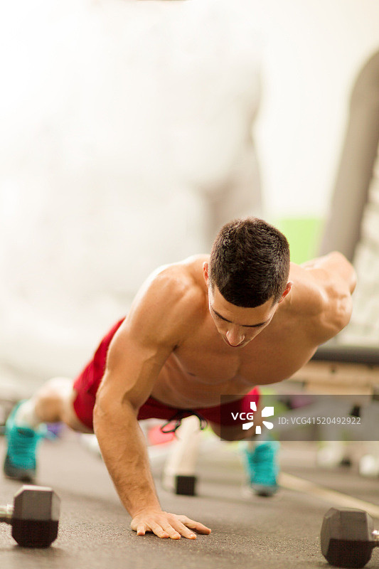 肌肉发达的男人在健身房单手做俯卧撑。图片素材