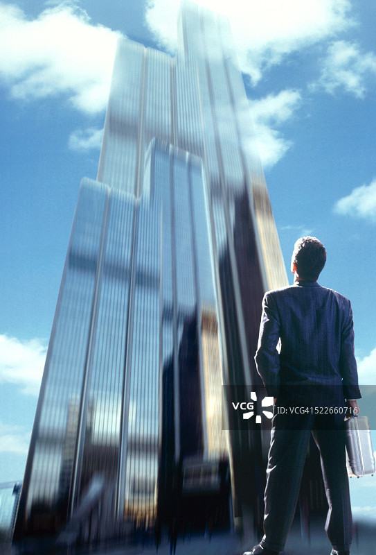 商人抬头望着摩天大楼图片素材
