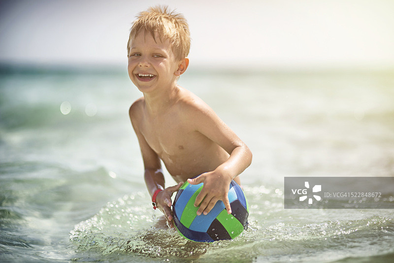 小男孩在海里玩球玩得很开心图片素材