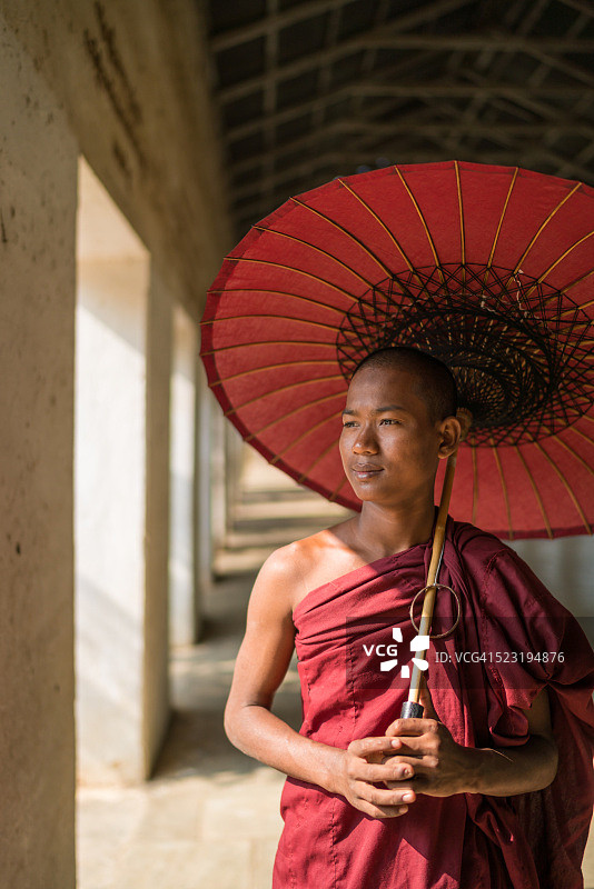 一位缅甸僧人撑着伞面朝阳光微笑图片素材
