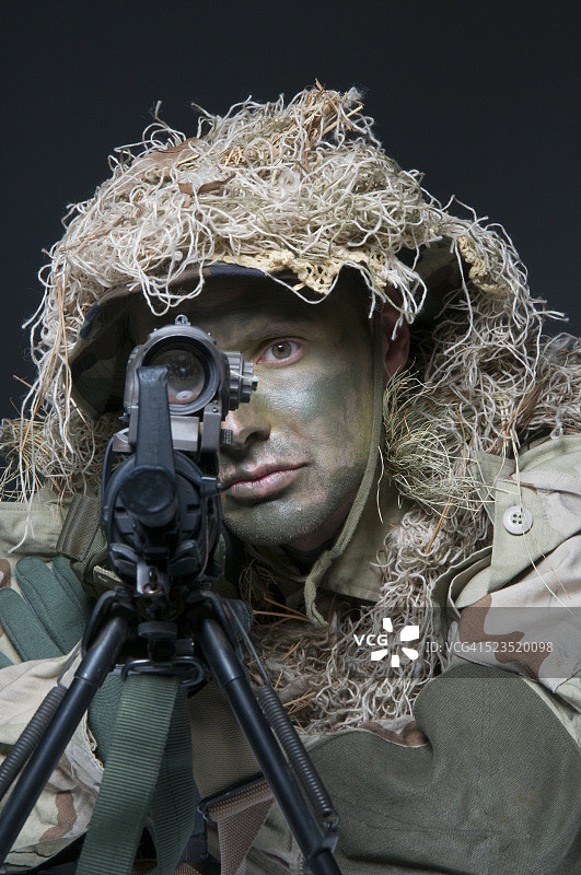 身着迷彩野战装备和吉利服的美国空降特种部队狙击手在狙击武器范围内观察图片素材