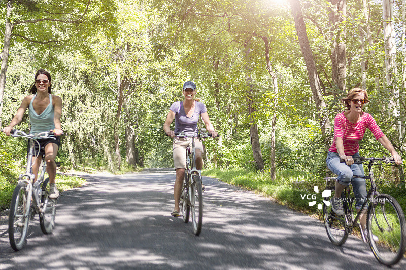 三个成熟的女人在乡间路上骑自行车图片素材