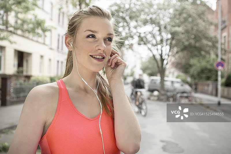 德国，下萨克森州，汉诺威，戴着耳机的年轻女性慢跑者的肖像图片素材