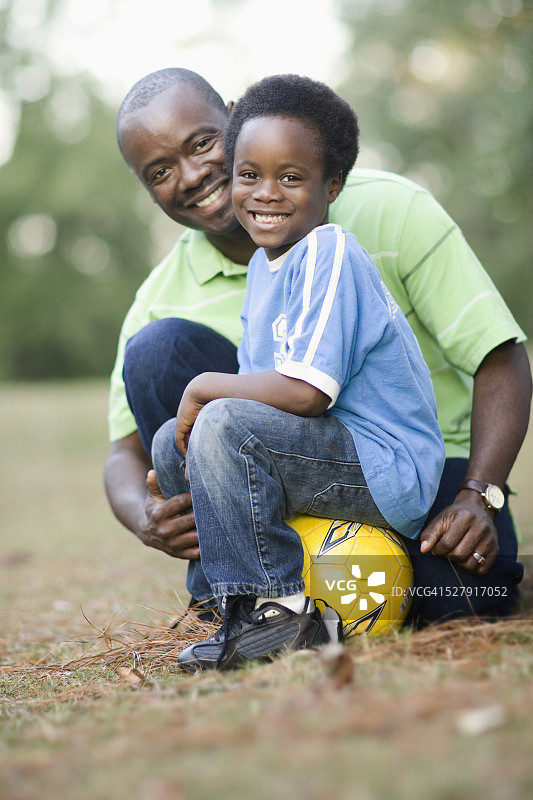 男孩和父亲坐在足球上图片素材