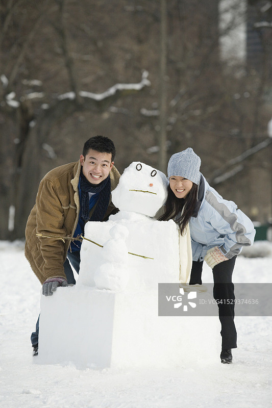 一对夫妇在雪人旁边微笑图片素材
