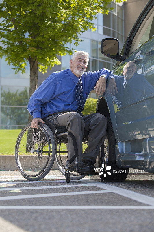 患有肌肉萎缩症和糖尿病的人坐在轮椅上，旁边是一辆无障碍货车图片素材