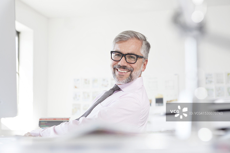 一个微笑的男人的肖像在他的办公桌在一个办公室图片素材