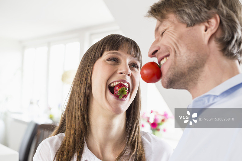 一对夫妇嘴里叼着草莓和西红柿图片素材